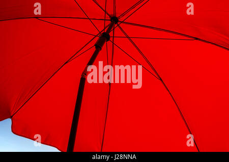 Unter einem roten Sonnenschirm an einem sonnigen Tag Stockfoto