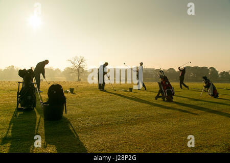 Golfspielerschwingen Golf Clubs in der frühen Morgensonne auf Praxis driving range in der Morgendämmerung. Stockfoto