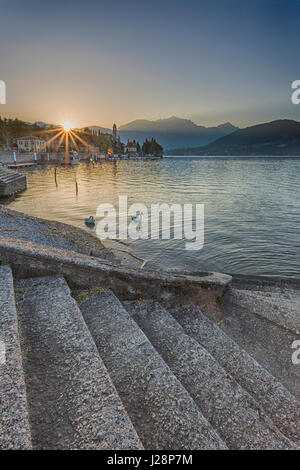 Treppe zum See mit Schwänen bei Sonnenaufgang mit der Sonne im Morgengrauen in Tremezzo auf der Westseite des Comer See, Italien im April Stockfoto