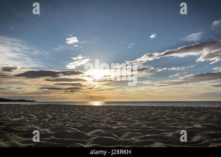 Leeren Strand in den frühen Morgenstunden in Costa Rei, Sardinien, Italien. Schöne Wolken, Sonnenaufgang und Sandstrand. Berge im Hintergrund. Stockfoto