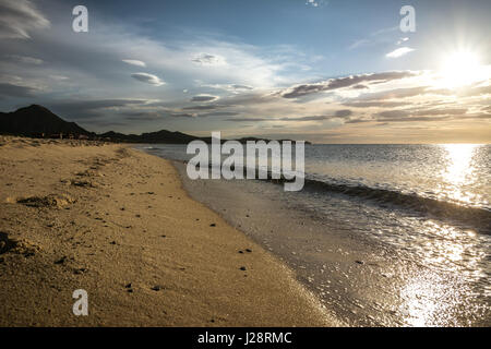 Leeren Strand in den frühen Morgenstunden in Costa Rei, Sardinien, Italien. Schöne Wolken, Sonnenaufgang und frische Spuren in den Sand. Niemand in der Szene. Stockfoto