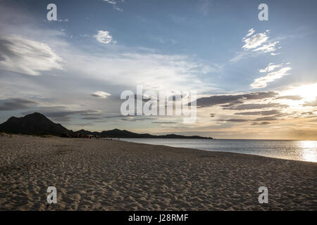 Leeren Strand in den frühen Morgenstunden in Costa Rei, Sardinien, Italien. Schöne Wolken, Sonnenaufgang und Sandstrand. Berge im Hintergrund. Stockfoto