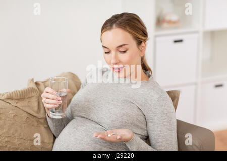 glücklich schwanger Frau mit Wasser und Pillen zu Hause Stockfoto