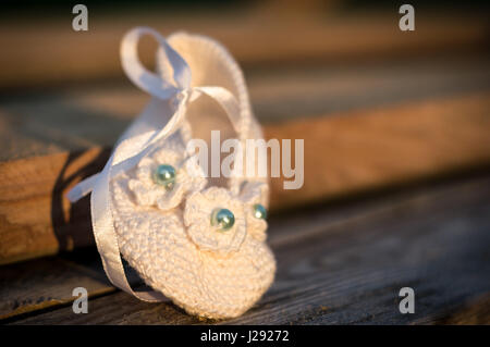 Handgefertigte weiße Baby Boot mit Perlen auf hölzernen Hintergrund an sonnigen Tag Stockfoto