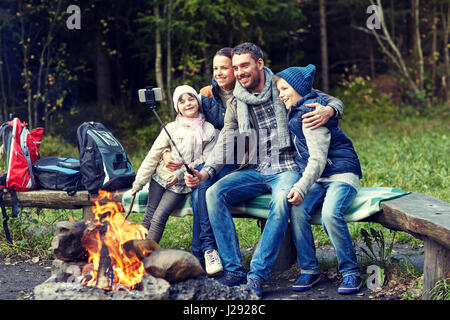 Familie mit Smartphone unter Selfie nahe am Lagerfeuer Stockfoto