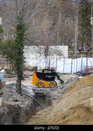 Tagesansicht des gelben Minibagger mit Schaufel in Aktion auf der Baustelle Stockfoto