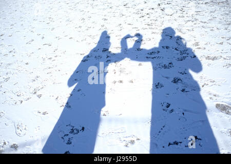 Silhouetten der Schatten des zwei Personen auf einem schneebedeckten Rasen. (Tiefenschärfe) Stockfoto