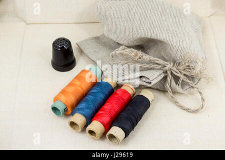 Stoff zum Nähen, Zubehör für Handarbeiten auf neuen Textil-Hintergrund. Spool-Faden, Schere, Fingerhut, Tapemeasure, Nähen Zubehör. Satz Stockfoto