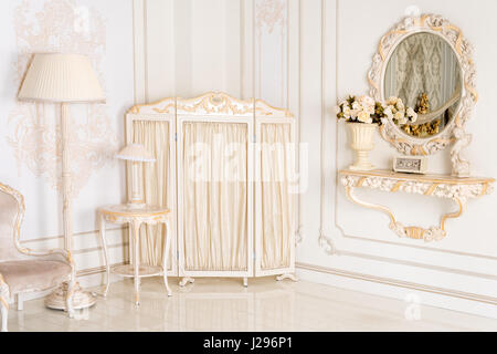 Luxus Schlafzimmer in hellen Farben mit Spiegel und Paravent. Elegantes klassisches Interieur Stockfoto