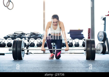 Schöne junge passen Frau in Turnhalle heben schwere Langhantel, Muskeln Stockfoto