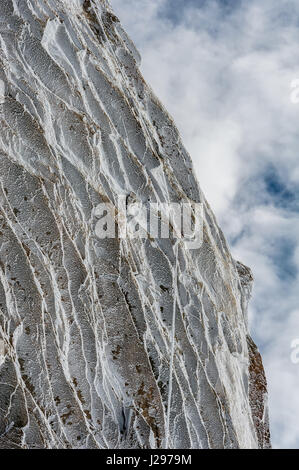 Eiskristalle und Oberfläche hoar gebildet aus über Nacht Einfrieren auf hohe alpine Felswand im Winter gegen teilweise Wolke bedeckt Himmel Stockfoto