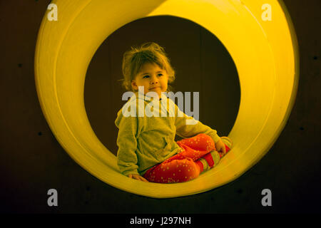 Kind genießt Klettern durch einen Tunnel in einen Kinderspielplatz im Freien. Stockfoto