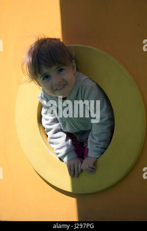 Kind genießt Klettern durch einen Tunnel in einen Kinderspielplatz im Freien. Stockfoto