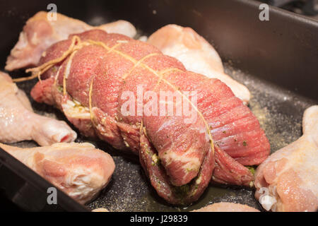 Gerollt und gebunden Flanke Steak und Chicken Drumsticks in den Ofen zum Backen platziert werden. Stockfoto