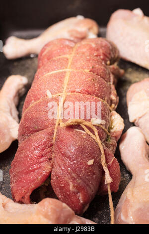 Gerollt und gebunden Flanke Steak und Chicken Drumsticks in den Ofen zum Backen platziert werden. Stockfoto