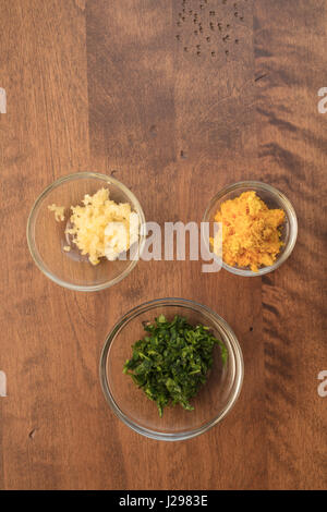 Knoblauch, Petersilie und Orange Schale in gemessenen Schalen für eine Schale Zubereitung von Speisen Stockfoto