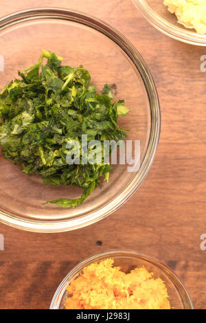 Knoblauch, Petersilie und Orange Schale in gemessenen Schalen für eine Schale Zubereitung von Speisen Stockfoto