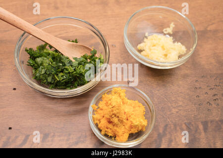 Knoblauch, Petersilie und Orange Schale in gemessenen Schalen für eine Schale Zubereitung von Speisen Stockfoto