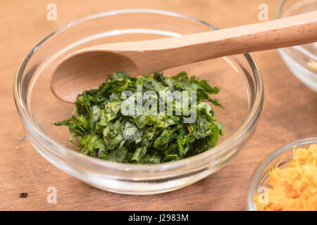 Knoblauch, Petersilie und Orange Schale in gemessenen Schalen für eine Schale Zubereitung von Speisen Stockfoto