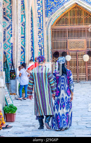 SAMARKAND, Usbekistan - 28 AUGUST: Paar gekleidet in traditionellen usbekischen Hochzeitskleidung - bunte und Muster von der Rückseite in Samarkand Registan. Stockfoto