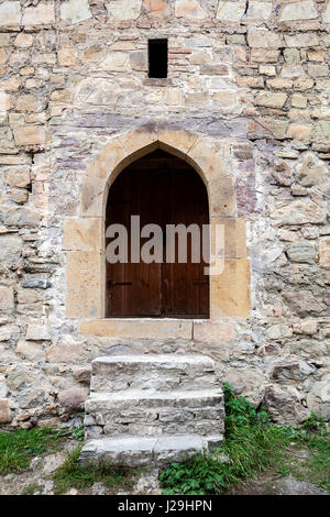 Alte Treppen und Holztür in eine Steinmauer. Stockfoto