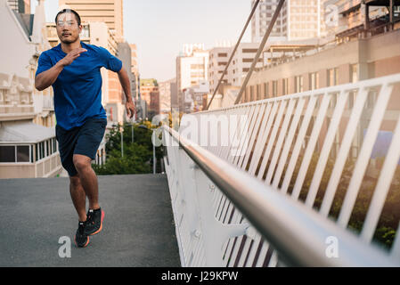 Sportliche jungen asiatischen Mann quer durch eine Stadtbrücke Stockfoto