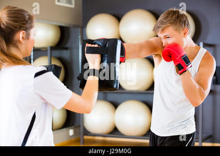 Engagierte Boxer Punching Bag statt vom Kursleiter Stockfoto