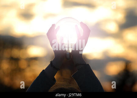 Energie-Glühbirne von Sonnenuntergang auf Hand-Konzept Stockfoto