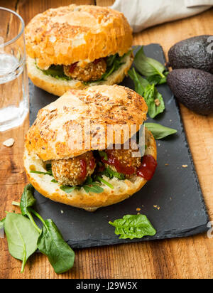 Gesunde vegane Burger mit Kichererbsen und Sesam Kugeln, Blätter frischer Spinat auf Holzbrett Stockfoto