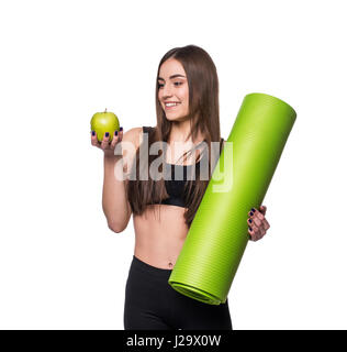 Porträt der lächelnde junge Frau hält aufgerollt Gymnastikmatte Yoga und grüner Apfel, isoliert auf weißem Hintergrund Stockfoto