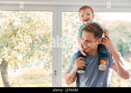 Kleinkind Jungen auf Vaters Schultern zu Hause Fenster Stockfoto