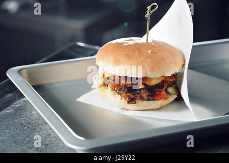 Leckere Burger mit Rindfleisch, Tomaten, Käse und Salat. zubereitet auf dem Grill montiert. Stockfoto