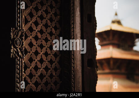 Detail von einem kunstvoll geschnitzten Fenster Shutter in den königlichen Palast und Museum in Patans Durbar Square, Nepal hautnah. Hari Shankar Pagode ist sichtbar Stockfoto