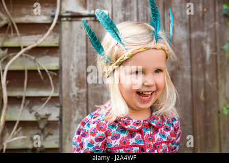 Glückliche kleine Mädchen in bunten indischen Stirnband stehen im Garten Stockfoto