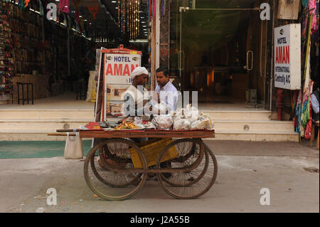 Straßenhändler stehen zu Ihrer Warenkorb außerhalb Hotel aman Internationale, Main Bazaar Straße in Paharganj in Delhi, Indien Stockfoto