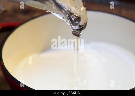 Klar dicke Flüssigkeit Gießen in einen Topf. Stockfoto