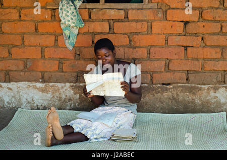 Malawi, Salima District, Kuntonya Dorf, Social Cash Transfer Program, Salome George ihrer Schulbücher zu lesen. Aufenthalt mit 5 Waisen. Erhält MK 3,000.00 pro Monat (17 USD). Geld wird verwendet, um Lebensmittel, Schuluniform und andere Grundbedürfnisse zu kaufen. Stockfoto