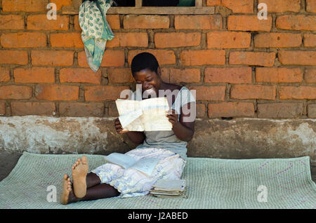 Malawi, Salima District, Kuntonya Dorf, Social Cash Transfer Program, Salome George ihrer Schulbücher zu lesen. Aufenthalt mit 5 Waisen. Erhält MK 3,000.00 pro Monat (17 USD). Geld wird verwendet, um Lebensmittel, Schuluniform und andere Grundbedürfnisse zu kaufen. Stockfoto