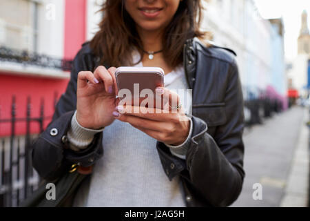 Junge Frau, die in der Straße, die mit Telefon, close-up-Ernte Stockfoto
