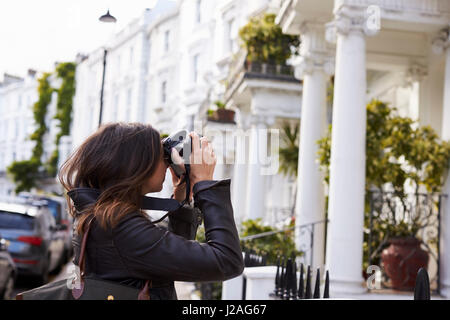 Junge Frau nehmen Foto in einer Residenzstadt Straße, Seitenansicht Stockfoto