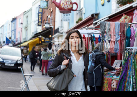 Gemischte Rassen junge Frau zu Fuß in Portobello Road Market, London Stockfoto