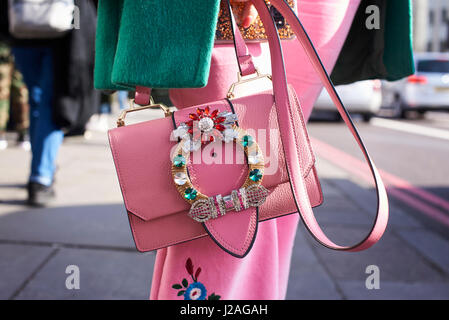 LONDON - Februar 2017: Innenfeldes Frau trägt rosa Rock mit rosa Miu Miu Handtasche und Mantel mit Blumenschmuck in der Straße während der London Fashion Week Stockfoto