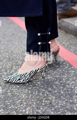 LONDON - Februar 2017: Niedrige Teil der Frau mit dekorativen Stifte in ihre Hose und Zebramuster, Kitten Heel Pantolette stehen auf der Straße während der London Fashion Week, vertikale Stockfoto