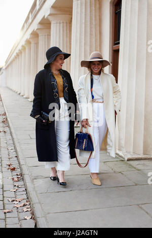 LONDON - Februar 2017: In voller Länge auf zwei modische Frauen tragen Mäntel und Hüte, die walking Street, London Fashion Week, Tag vier. Stockfoto