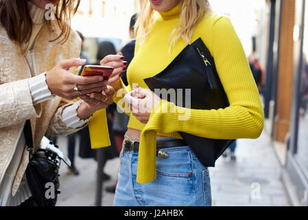 Zwei trendige Frauen mit einem Smartphone in der Straße, Mittelteil Stockfoto