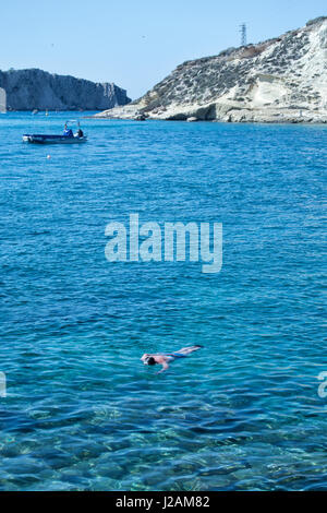 Tremiti-Inseln. Mann, Schwimmen im transparenten Meerwasser mit Booten und Felsen im Hintergrund Stockfoto