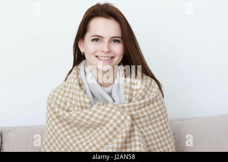 Mädchen sitzt auf dem Sofa unter den Teppich. Stockfoto