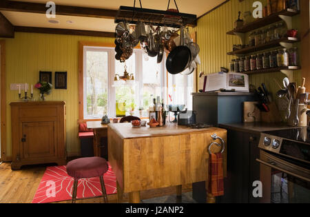 Hängende Töpfe und Pfannen über eine hölzerne AP-Tisch in der Küche im Landhausstil Wohnhaus Stockfoto