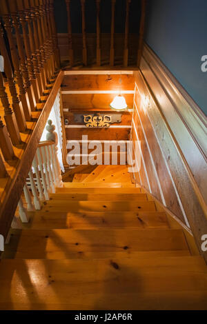 Eine Holztreppe führt in die untere Etage in ein gestapeltes Blockhaus. Stockfoto