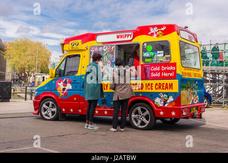 Zwei Kunden, die ein Eis von einem bunten Eiswagen kaufen Stockfoto